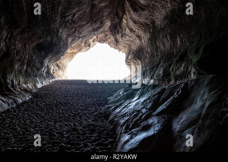 Sea Cave auf Cala Luna Sandstrand in Sardinien, Italien. Licht am Ende der Höhle Stockfoto