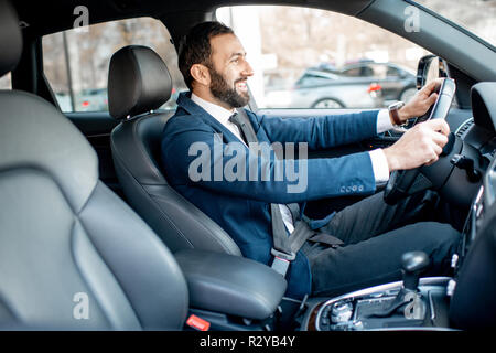 Schöne bärtige Geschäftsmann im Anzug, der ein Auto fährt in der Stadt angezogen Stockfoto