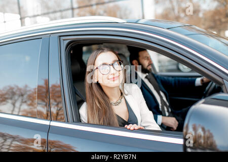 Elegante Geschäftsfrau, schauen aus dem Fenster fahren Luxusauto mit Geschäftsmann in der Stadt Stockfoto