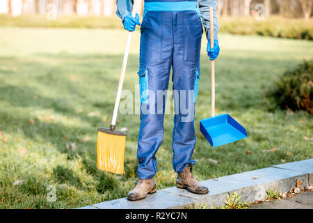 Sweeper in Uniform mit der Reinigung der Werkzeuge im Garten, 7/8-Bild ohne Gesicht Stockfoto