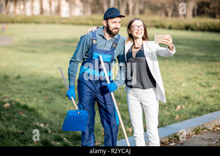 Geschäftsfrau und Sweeper, selfie Foto zusammen im Freien. Armut und Reichtum Konzept Stockfoto