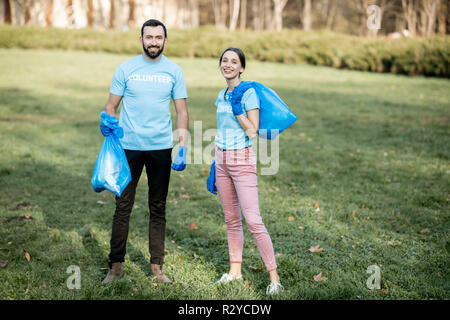 Portrait Of Happy Freiwillige in blauen T-Shirts mit Taschen voller Müll nach dem Park Reinigung Stockfoto