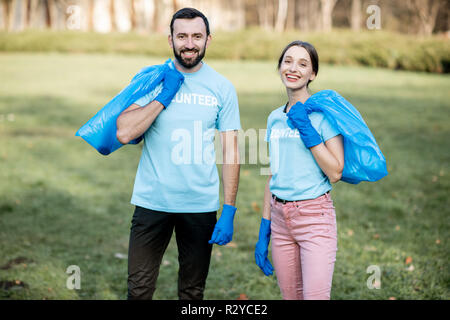 Portrait Of Happy Freiwillige in blauen T-Shirts mit Taschen voller Müll nach dem Park Reinigung Stockfoto