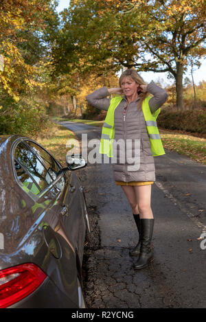 Frau Kraftfahrer durch ihr Auto setzen auf eine reflektierende Sicherheitsweste Stockfoto