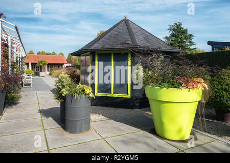 Appeltern, Niederlande, September 29, 2017: Vor der sechseckigen Pavillon ist eine riesige gelbe Blume, und zwei Ölfässer mit Pflanzen gefüllt ein Stockfoto