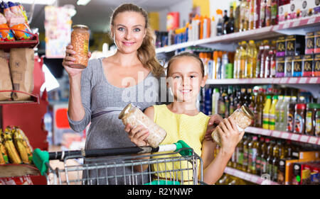 Fröhliche positive Mutter mit Jugendmädchen Demonstration ihrer Wahl in Essen Abteilung im Supermarkt Stockfoto