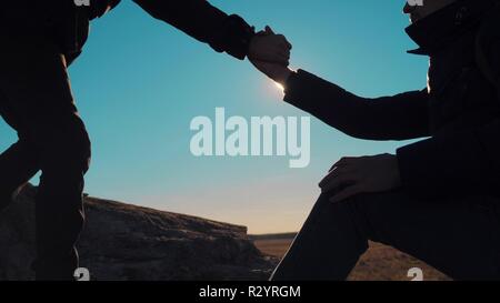 Teamarbeit business travel Reise. zwei Männer mit Rucksäcken wandern jedes anderen Silhouette in Bergen mit Sonnenlicht helfen. Slow Motion Video. teamwork Freundschaft wandern helfen, Vertrauen einander Hilfe die Silhouette in Bergen, sunrise Lebensstil Stockfoto