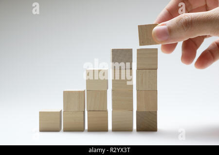 Nahaufnahme, Geschäftsmann, Hand arrangieren Holz Würfel Stapeln wie Schritt Treppe. Business Konzept Wachstum Erfolg. Stockfoto