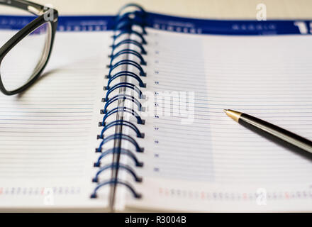 Brillen und einen Stift auf eine leere Spirale Tagebuch Agenda. Konzept und Zeitplan Stockfoto