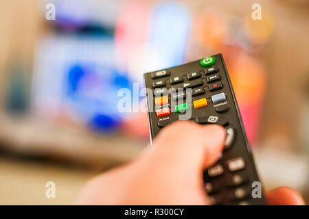 Eine Hand Drücken einer Taste der Fernbedienung, um die Kanäle vor einem verschwommenen TV-Bildschirm ändern. Stockfoto