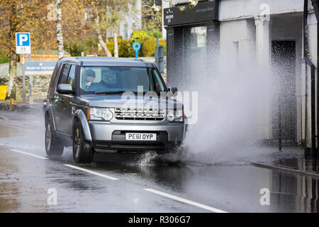 Autofahrer zu schnell gefahren durch grosse Pfützen einweichen Fußgänger und Unterkunft in Ambleside, Cumbria, Großbritannien. Stockfoto