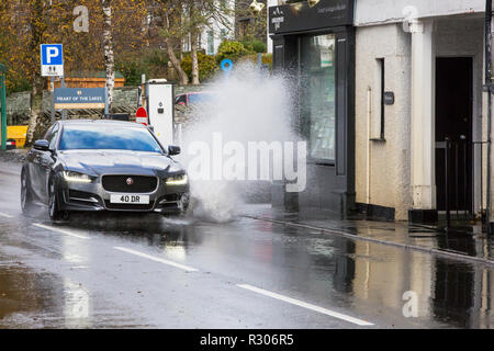 Autofahrer zu schnell gefahren durch grosse Pfützen einweichen Fußgänger und Unterkunft in Ambleside, Cumbria, Großbritannien. Stockfoto