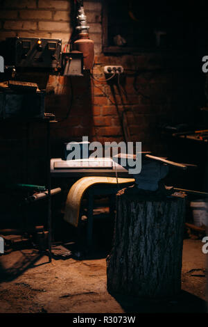 Ein alter Amboss zu einem holzsockel steht in einem eigenen Schmiede workshop befestigt Stockfoto