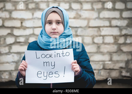 Flüchtling Mädchen mit einer Inschrift auf einem weißen Blatt' Blick in meine Augen' Stockfoto