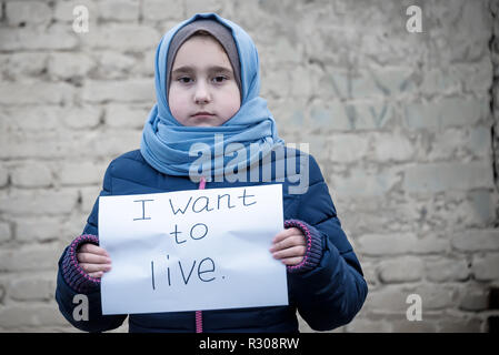 Flüchtling Mädchen mit einer Inschrift auf einem weißen Blatt "Ich möchte leben" Stockfoto