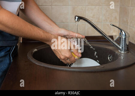 Foto von Seite der Hände des Menschen waschen Transparente Becher in Waschbecken Stockfoto