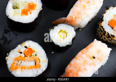 Typische asiatische Küche auf schwarze Küche Schiefer. Sushi - futomaki und Nigiri. Roher Fisch mit Reis und Gemüse. Stockfoto