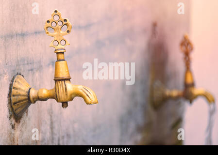 Zwei alte öffentlichen Hähnen in Istanbul, Türkei. Fließendes Wasser aus dem Wasserhahn im Hintergrund. Stockfoto