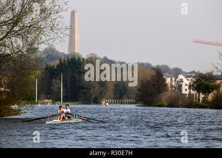 Zwei junge Männer Rudern auf dem Fluss Liffey, mit Wellington Monument im Hintergrund Stockfoto