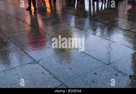 Reflexionen von Menschen in Callao in der Regen während eines dunklen am späten Nachmittag am Sonntag. Stockfoto