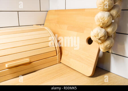 Brot bin. Ansicht der Küche Zähler mit Schneidbrett, die an der Wand hängen ein paar Köpfe von Knoblauch. Stockfoto