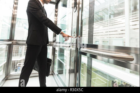 Mann durch Drücken auf die Taste. Das Aufdrücken mit dem Finger Fahrstuhl drücken. Geschäftsmann in Heben Stockfoto