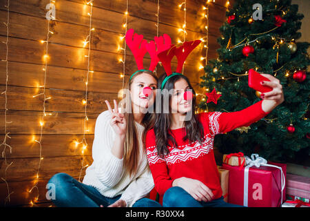 Lächelnd Freundinnen ein selfie mit Smartphone. Weihnachtliche Stimmung. Stockfoto