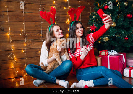 Lächelnd Freundinnen ein selfie mit Smartphone. Weihnachtliche Stimmung. Stockfoto