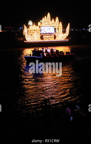 Phnom Penh feiert Bon Om Touk, der Kambodschanischen Water Festival. Eine beleuchtete float wirft seine Reflexion über den Tonle Sap Fluss. Silhouette der touristischen Riverboat im Vordergrund © kraig Lieb Stockfoto