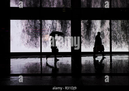 London, Großbritannien. Nov 2018 20. Wetter in Großbritannien: Oxford Street im Regen, Shopper Spaziergang, vorbei an einem riesigen video Wand an der Londoner Oxford Street. 20. November 2018 Credit: Thomas Bowles/Alamy leben Nachrichten Stockfoto