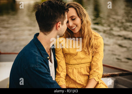 Romantisches Paar in einem Boot zusammen zu sitzen und zu reden. Junger Mann und Frau in Liebe zusammen in einem Boot auf einem Datum zu sitzen. Stockfoto