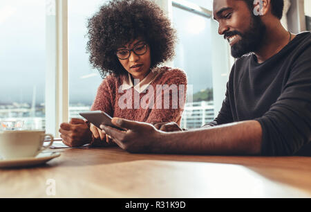 Afrikanische männlichen und weiblichen business Personen Ideen bei der Arbeit zusammen zu sitzen. Mitarbeiter im Büro an Tablet PC mit eine Tasse Kaffee suchen. Stockfoto