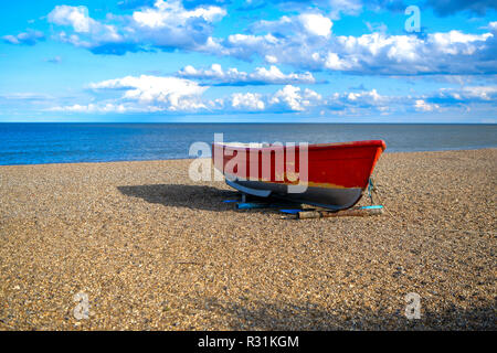 Foto von einem rot-weißen Boot auf dem Sand, Kiesel am Meer. Großbritannien Stockfoto