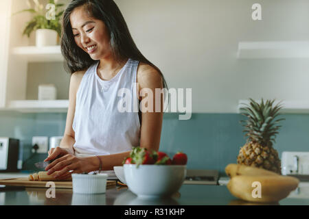 Frau vorbereiten gesunder Salat von frischen Früchten in der Küche. Weiblich, gesundes Frühstück am Morgen nach dem Training. Stockfoto