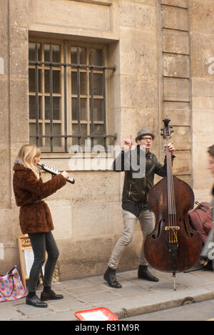 Street artist in Le Marais, Paris, unter Steinbögen stehend, Arcade, tragen schwarze Kleidung und Hut und ein roter Schal. Fluchtpunkt. Stockfoto