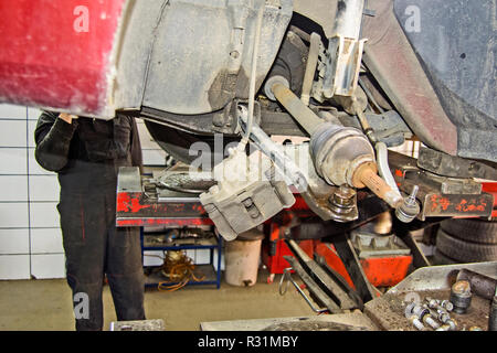 Der Mechaniker in der Werkstatt ersetzt das Lager auf die Vorderachse des Wagens. Stockfoto