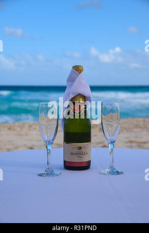 Flasche Champagner und zwei Gläser auf einem Tisch mit Strand und Meer im Hintergrund Stockfoto