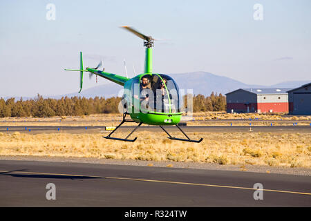 Ein Ausbilder und Flugschüler fliegen zwei - Sitz R22 Beta II Hubschrauber durch die Robinson helicopter Company, in einer kleinen Stadt Flughafen in Bend, Oregon Stockfoto