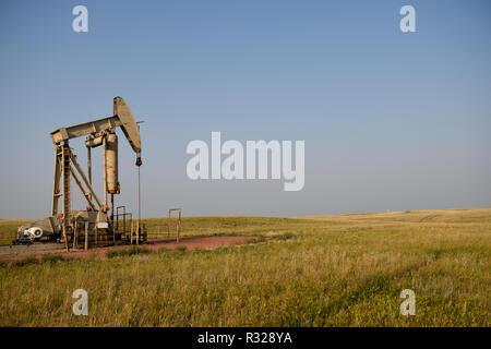 Öl und Gas Pumpe jack, gut sitzen und ländlichen Gebieten bei Sonnenuntergang, Niobrara Schiefer von Wyoming, mit kopieren. Stockfoto