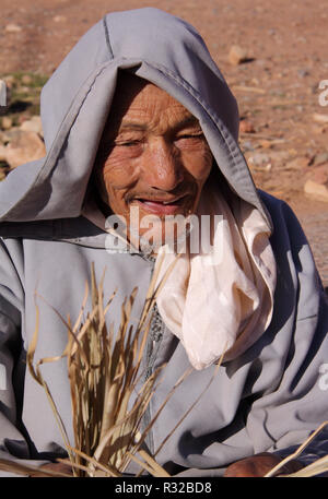 Marrakesch, Marokko - 21,02,2012: Eine freundliche alte typisch gekleidet Berber mann Handwerk Gurte von Stroh in den Ausläufern des Hohen Atlas. Stockfoto