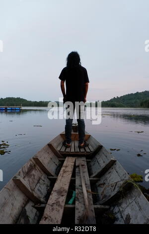 Mann, der vor kleinen Boot Stockfoto