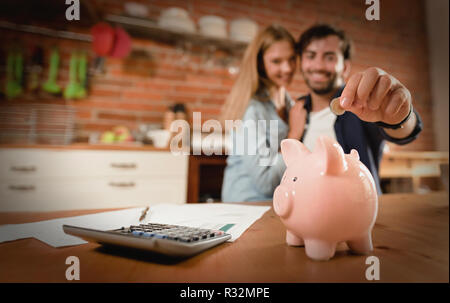 Glückliches Paar einfügen Münze im Sparschwein. Home Haushalt, Familie Finanzen Konzept. Foto breit mit Platz für Ihren Text Stockfoto