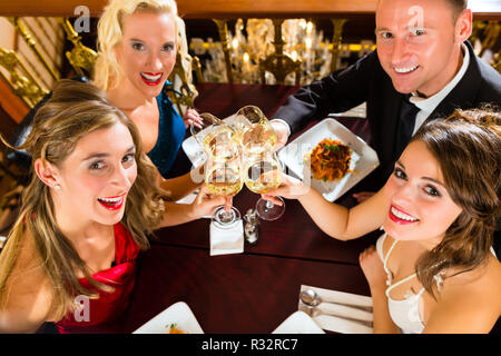 Freunde in einem sehr guten Restaurant stoßen Stockfoto