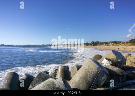 Betonsteine Schutz der Jetty von Santa Cruz Hafen, Sandstrand im Hintergrund, Kalifornien Stockfoto