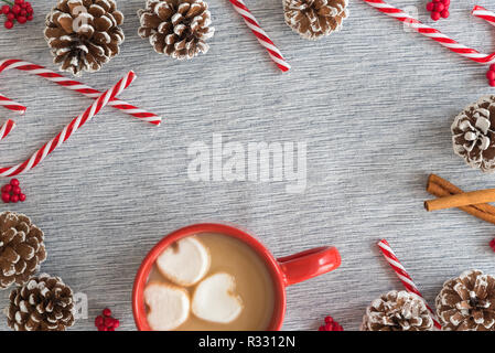 Rot Tasse heiße Schokolade und Marshmallows in Herzform mit Rahmen von Zuckerstangen und kiefernzapfen Stockfoto