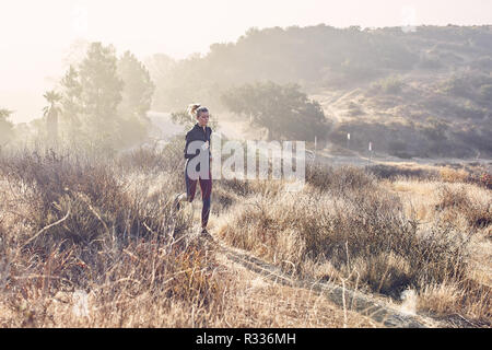 Schönen Kaukasischen weiß Frau läuft auf dem Trail in der Morgensonne Stockfoto