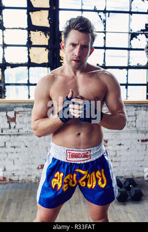 Kaukasische Mann Schatten Boxen in Wraps und Muay Thai Shorts Stockfoto