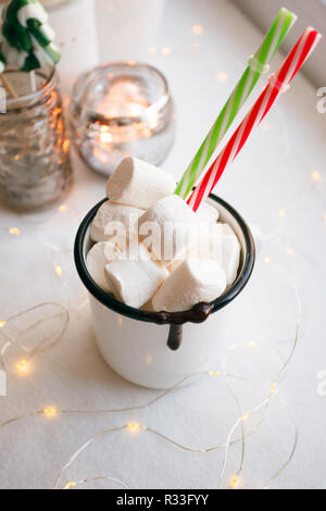 White Marshmallows in eine Schale, Weihnachten Zuckerstangen und Spielzeug Schlitten auf einem weißen Tisch. Weihnachten Neujahr Thema Stockfoto