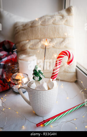 White Marshmallows in eine Schale, Weihnachten Zuckerstangen und Spielzeug Schlitten auf einem weißen Tisch. Weihnachten Neujahr Thema Stockfoto