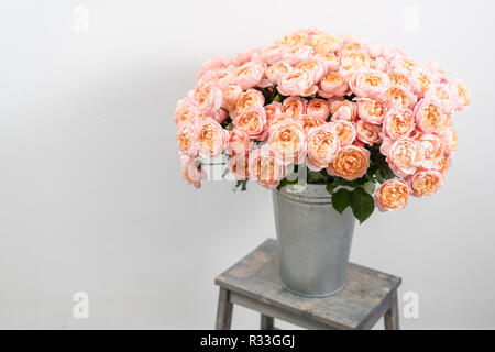 Großen Luxus helle Blumenstrauß peony Rose auf Holztisch. Garten spray Rosen rosa und Pfirsich Farbe. Blumenstrauß in Vase aus Metall Stockfoto